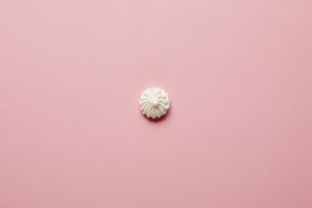 Bovenaanzicht van kleine witte meringue in het midden op de roze achtergrond - Foto, afbeelding