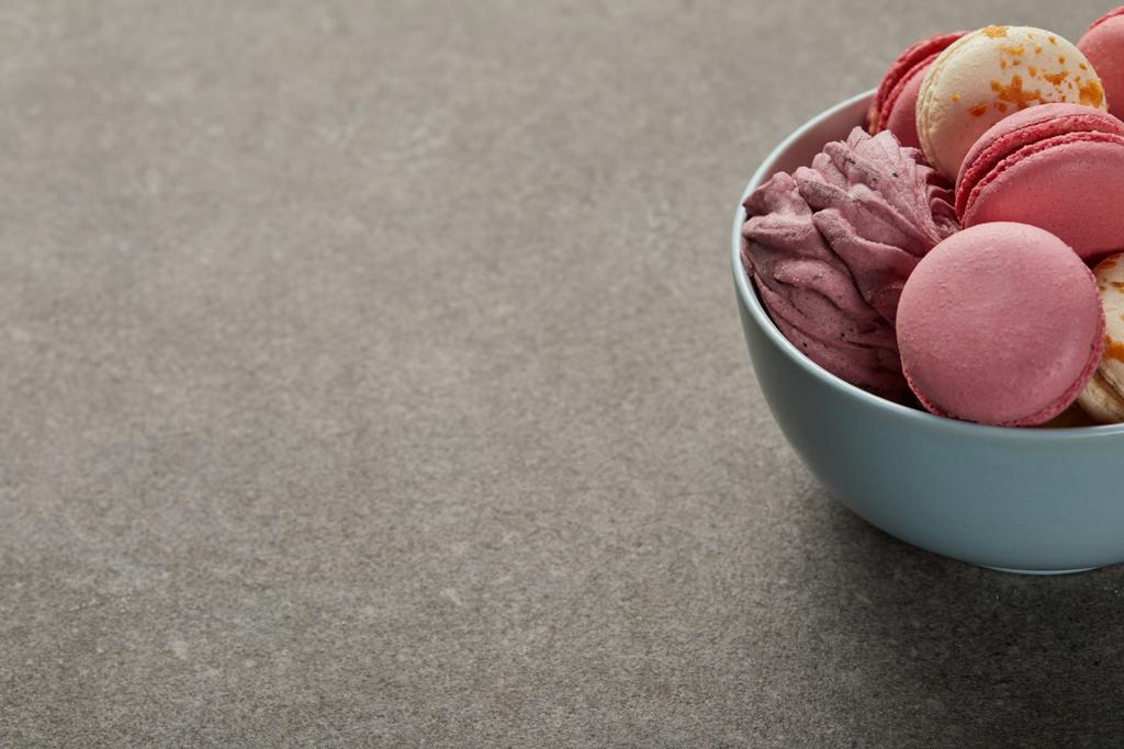 Delicious pink and white macaroons with zephyr in blue bowl on gray background - Photo, Image