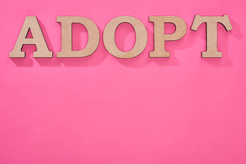 top view of cardboard word adopt on pink background with copy space - Photo, Image