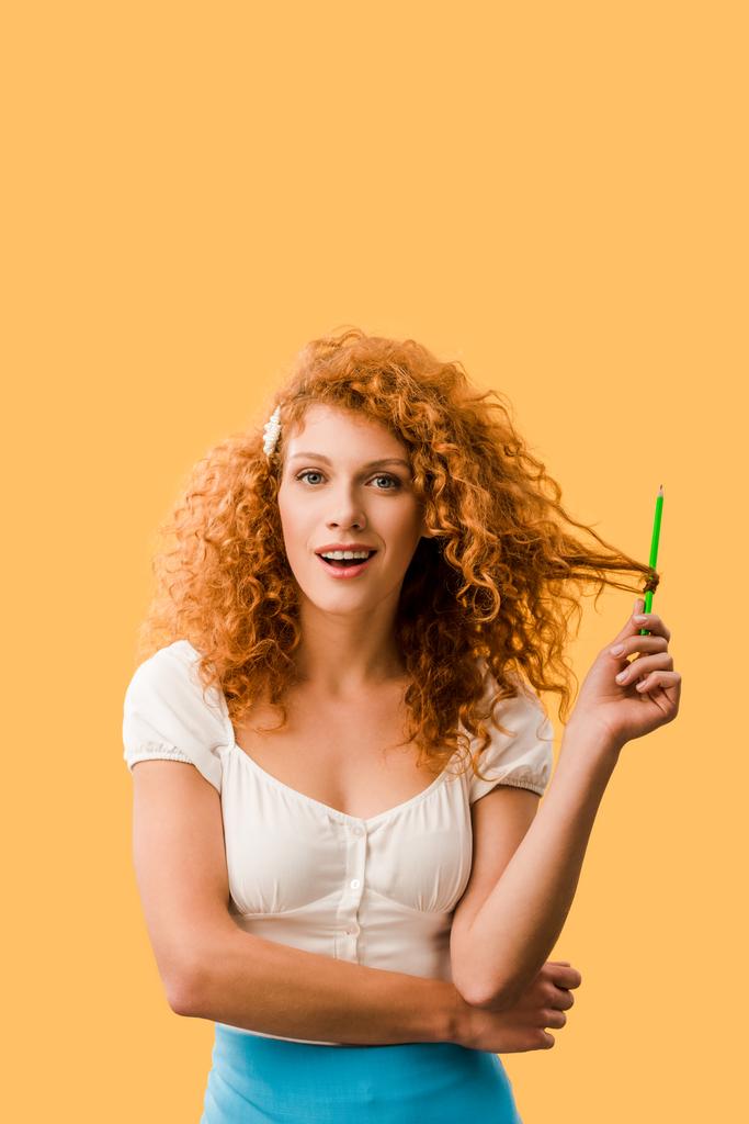 geschokt Redhead meisje met potlood geïsoleerd op geel - Foto, afbeelding