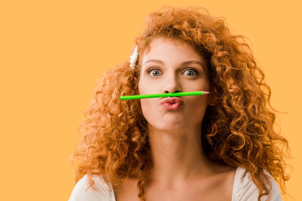 attractive redhead woman with pencil isolated on yellow - Photo, Image