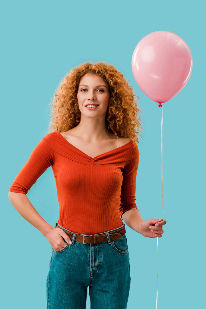 jonge roodharige vrouw met roze ballon geïsoleerd op blauw - Foto, afbeelding