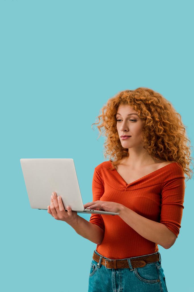 όμορφη κοκκινομάλλα γυναίκα χρησιμοποιώντας φορητό υπολογιστή απομονωθεί στο μπλε - Φωτογραφία, εικόνα
