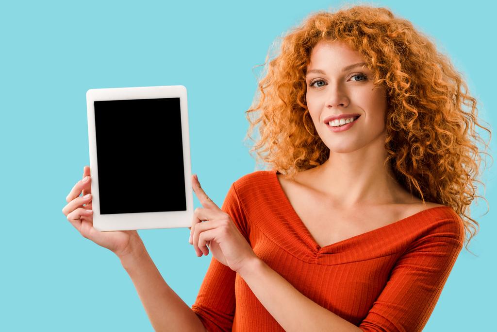 χαρούμενο κορίτσι που δείχνει το ψηφιακό δισκίο με κενή οθόνη απομονωμένη στο μπλε - Φωτογραφία, εικόνα