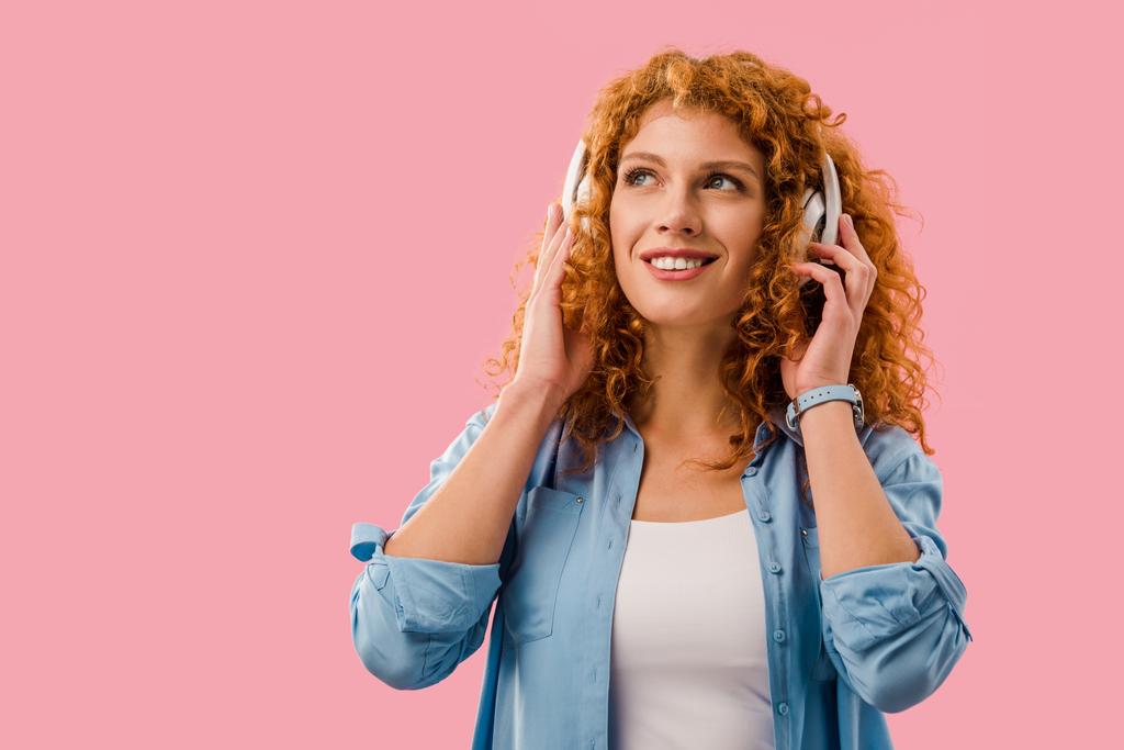 χαμογελαστή σγουρά κορίτσι ακούγοντας μουσική στα ακουστικά, απομονωμένο σε ροζ - Φωτογραφία, εικόνα