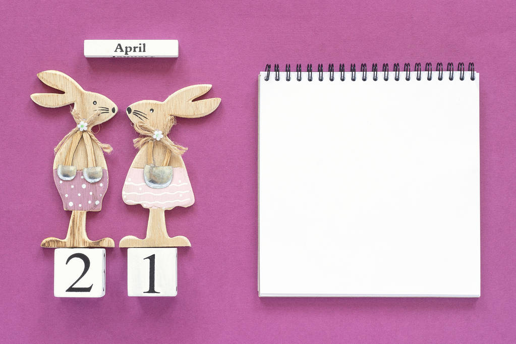 Kalender april 21 en paar houten Pasen Bunnies, wit Kladblok op paarse papier achtergrond - Foto, afbeelding