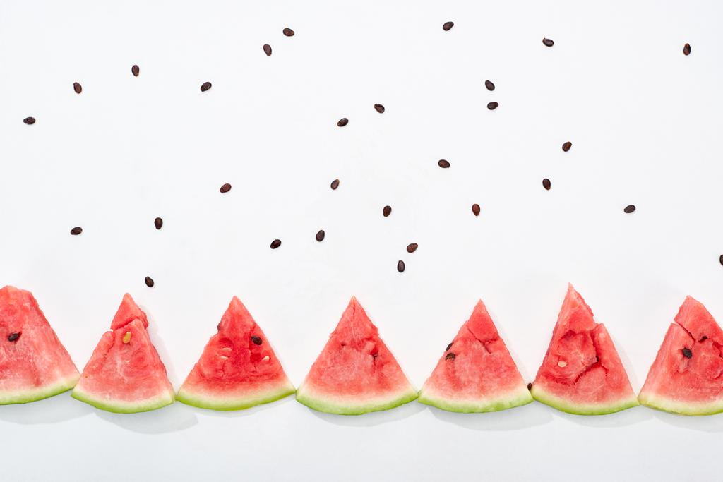 flache Lage mit köstlichen saftigen Wassermelonenscheiben und verstreuten Samen auf weißem Hintergrund - Foto, Bild