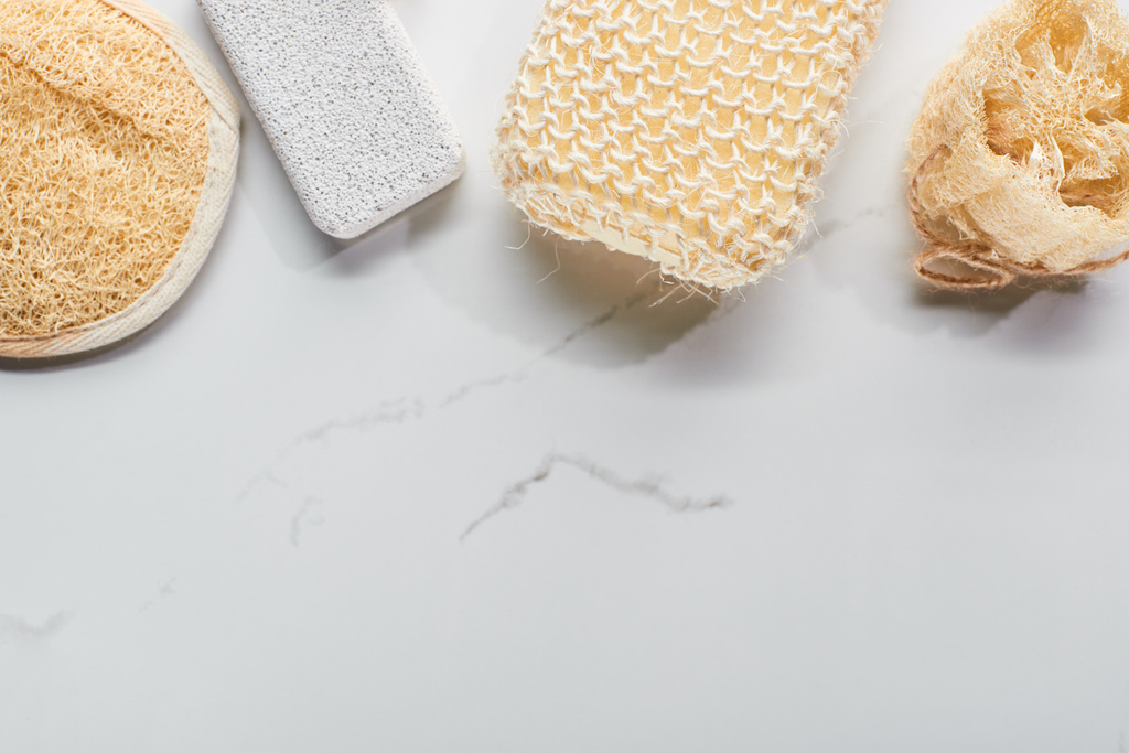 mermer yüzeyinde pomza taşı, loofah ve banyo süngerlerinin üst görünümü - Fotoğraf, Görsel