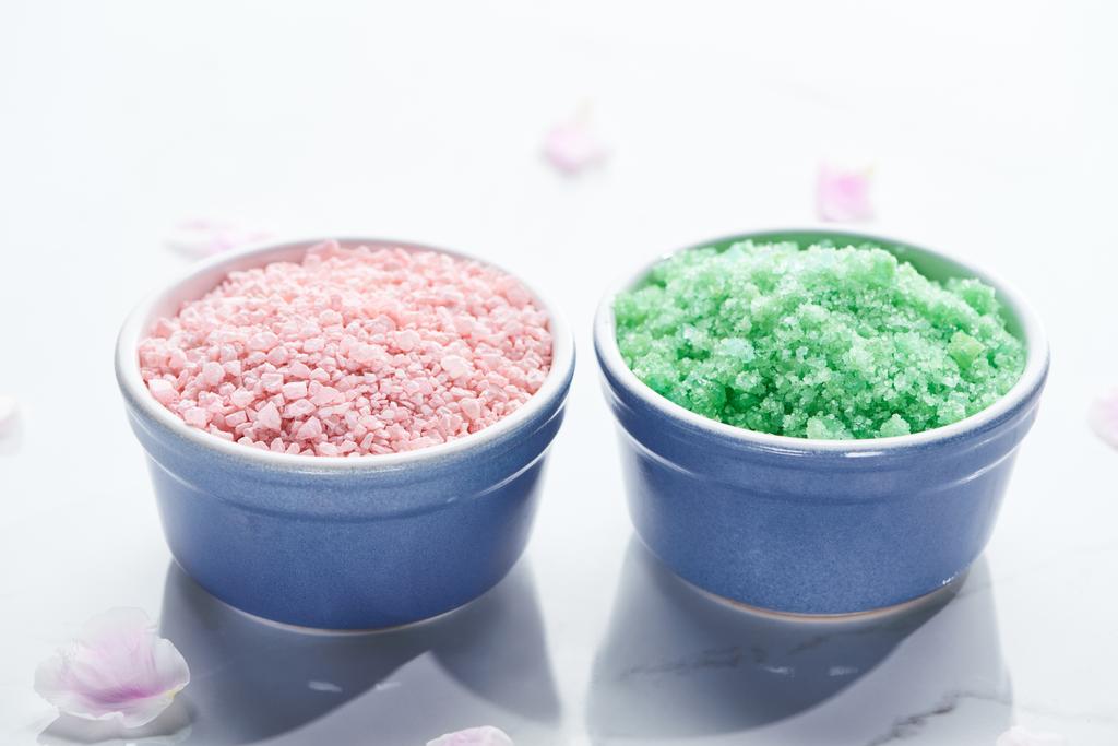 Widok z bliska niebieskie kubki z soli do kąpieli na białej powierzchni z różowymi płatkami - Zdjęcie, obraz