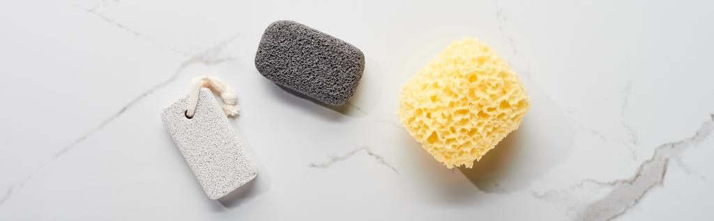 panoramic shot of light and dark gray pumice stone and bath sponge on marble surface - Photo, Image