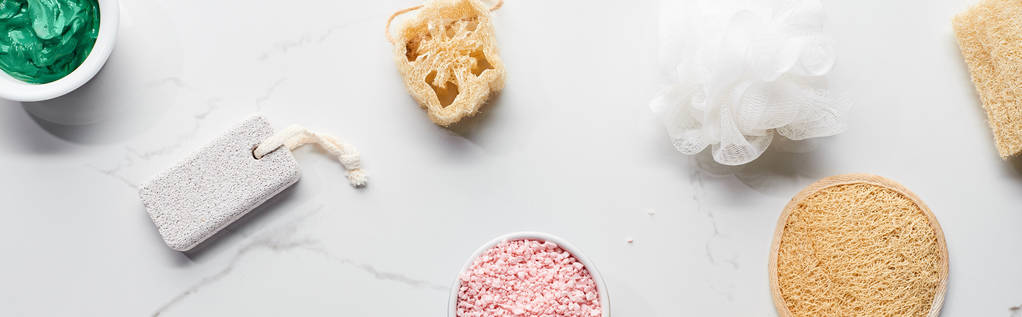 πανοραμικό σφηνάκι από Σφουγγάρια μπάνιου, σφουγγάρι, ελαφρόπετρα και φλιτζάνια με φυσικά προϊόντα ομορφιάς σε μαρμάρινη επιφάνεια - Φωτογραφία, εικόνα