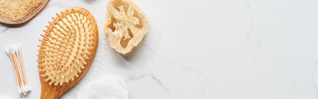 tiro panorâmico de cotonetes, escova de cabelo e loofah na superfície de mármore
 - Foto, Imagem