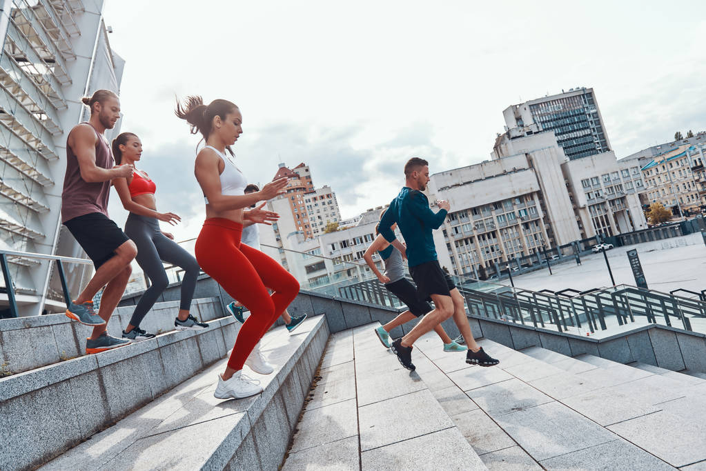 Группа молодых людей в спортивной одежде бегает по лестнице вниз по городу
  - Фото, изображение