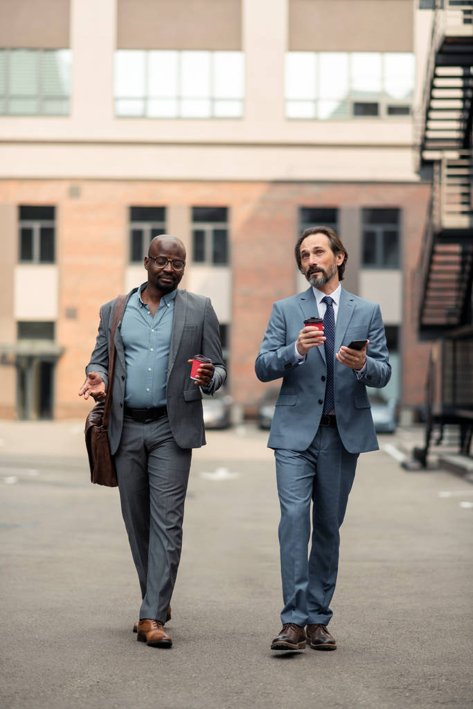 Επιχειρηματικοί εταίροι που κρατάνε καφέ και κατευθύνονται προς το γραφείο - Φωτογραφία, εικόνα