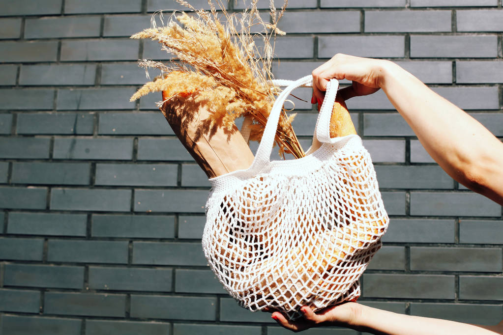vrouw met brood in haar gebreide tas  - Foto, afbeelding
