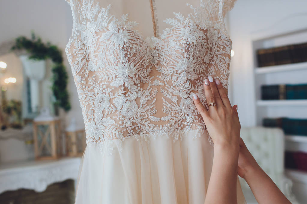 豊かなピンクのウェディングドレスは、白い部屋でシャンデリアにハングアップ. - 写真・画像