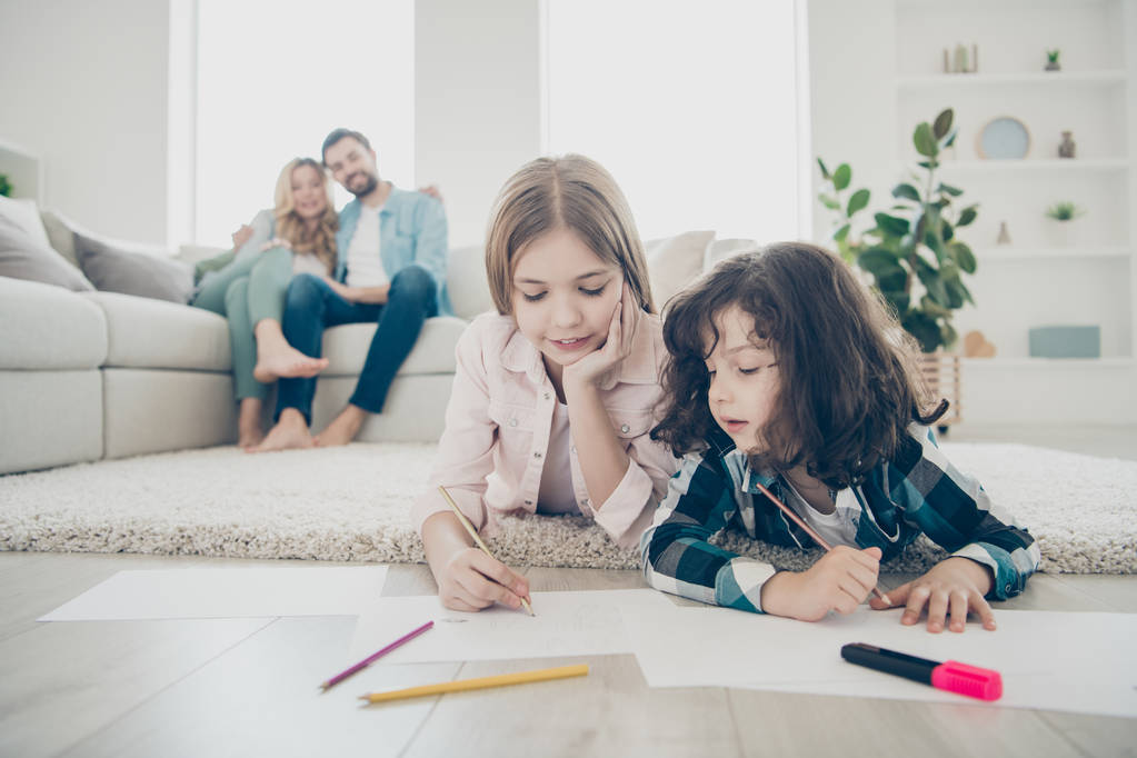 Zdjęcie z Big Family dwoje dzieci leżącej podłodze puszyste dywan tworzenia rysunków, podczas gdy rodzice cieszyć oglądania przyjazne adoptowane dzieci - Zdjęcie, obraz