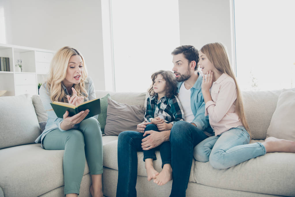 Jonge grote familie twee kinderen comfortabel zitten sofa luisteren Mama lezing spannende sprookje - Foto, afbeelding