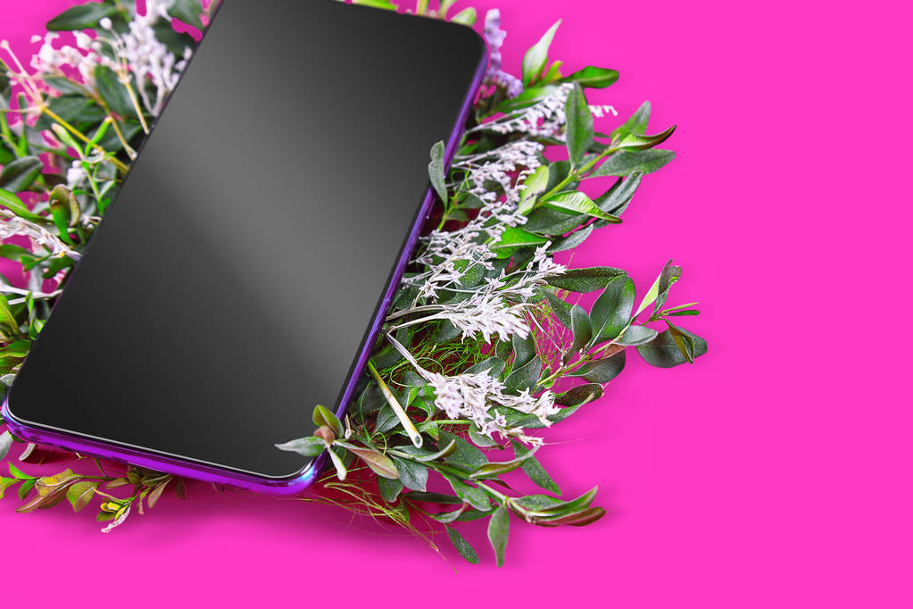 Creative layout flat lay with smartphone and flowers on pink bacground. Smartphone is frame lay on different flowers. Sale, modern technologies, post card concept. Mockup cellphone creative layout - Photo, Image