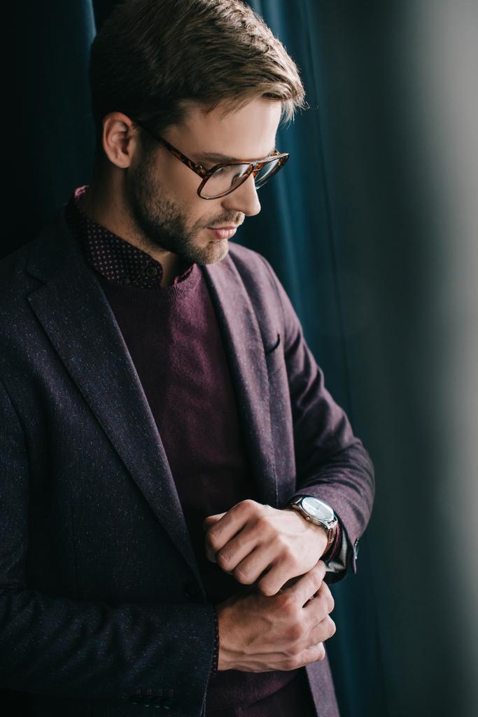 стильний молодий чоловік в піджаку і окулярах стоїть біля завіси
 - Фото, зображення