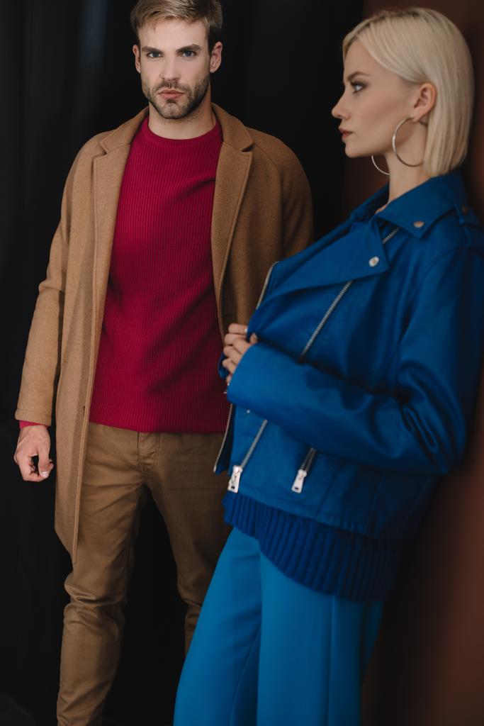 стильная пара в осенних нарядах, стоящая у занавеса
 - Фото, изображение