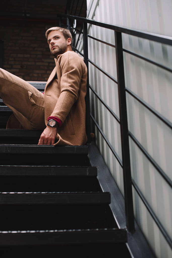 cher homme en manteau brun assis sur les escaliers et regardant loin
 - Photo, image
