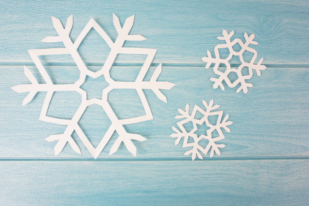 орігамі паперові сніжинки на синій дерев'яній поверхні столу, вид зверху
  - Фото, зображення