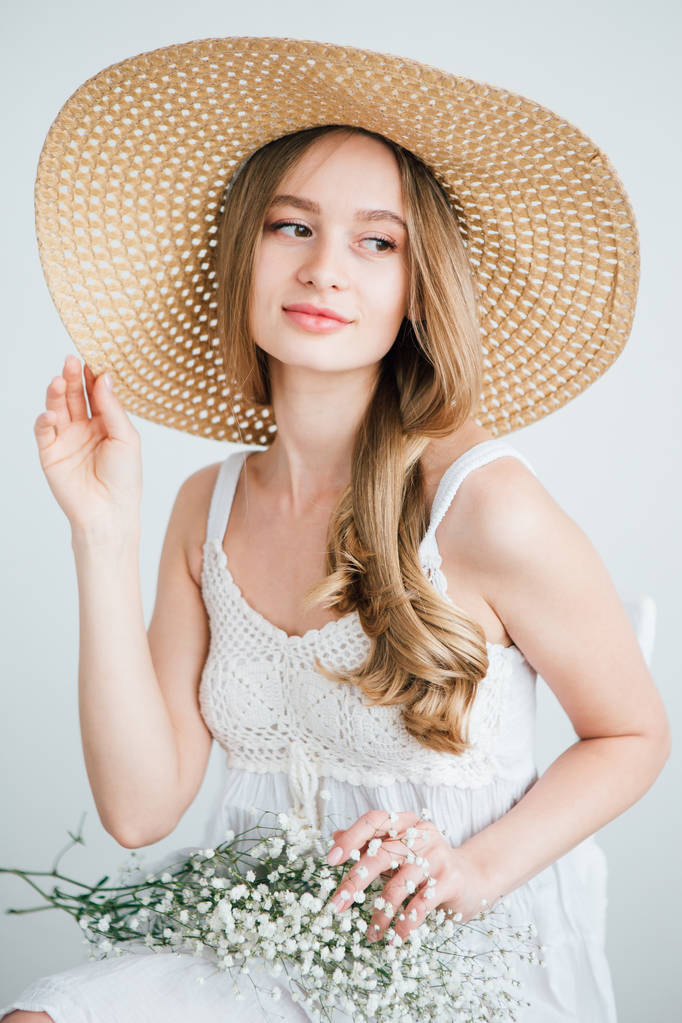 Chica con el pelo largo y sombrero posando con un ramo de flores blancas
 - Foto, imagen
