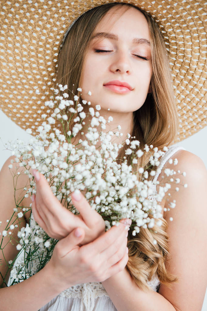 Chica con el pelo largo y sombrero posando con un ramo de flores blancas
 - Foto, Imagen
