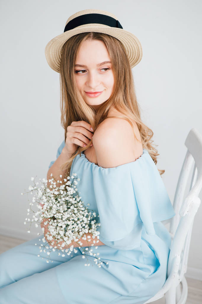 Chica con el pelo largo y sombrero posando con un ramo de flores blancas
 - Foto, imagen