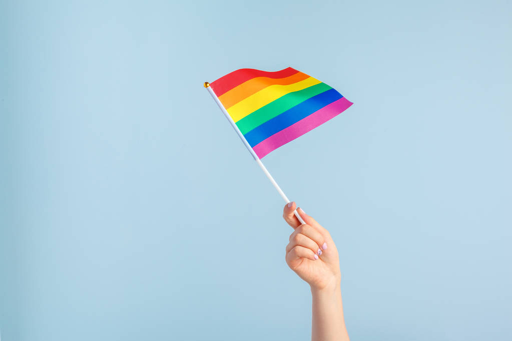 Gay flags in women's hand on grey background - Photo, Image