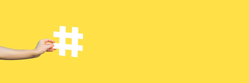 sarı arka plan, pazarlama sembolü ve sosyal medya kavramı üzerinde büyük büyük beyaz hashtag işareti gösteren insan elinin kırpılmış görünümü  - Fotoğraf, Görsel