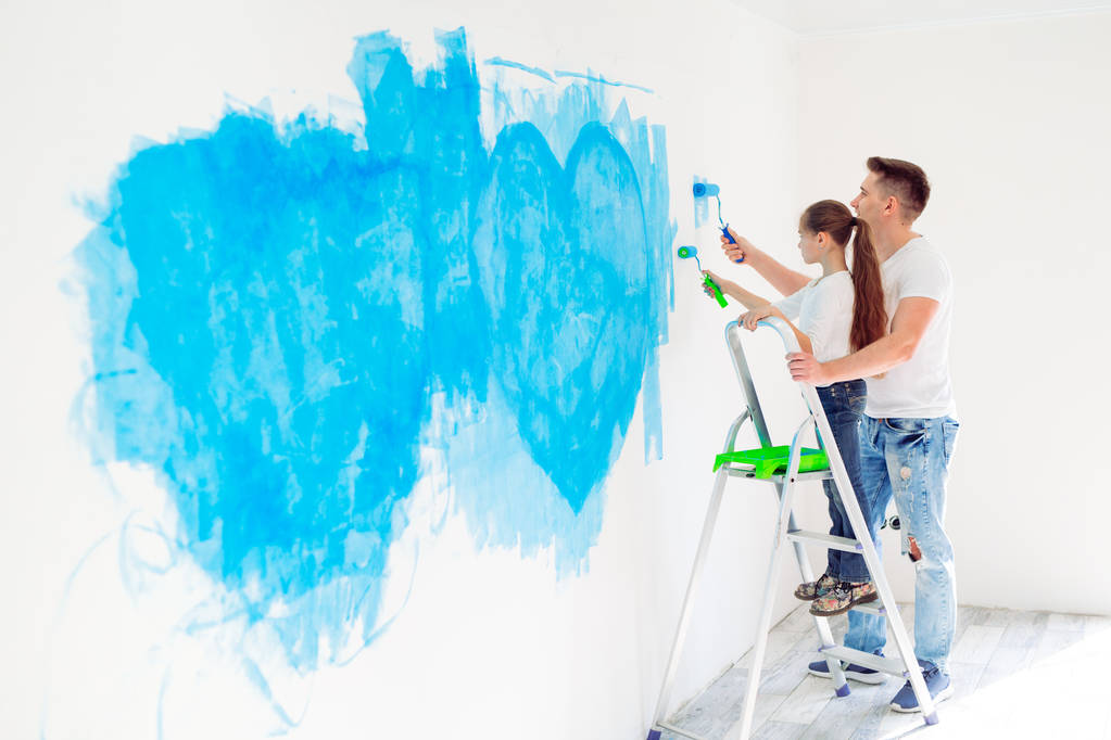 Ο πατέρας και η κορούλα του βάφουν έναν τοίχο σε νέο σπίτι.. - Φωτογραφία, εικόνα