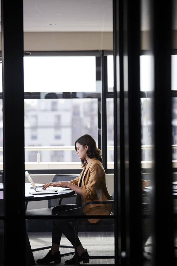 Femme d'affaires créative blanche millénaire travaillant seule dans une salle de réunion, verticale
 - Photo, image