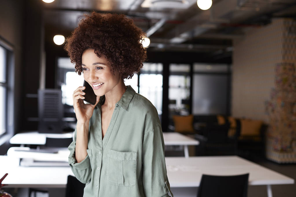 Тисячолітнє чорне жіноче творче становище у відкритому офісі з використанням смартфона, крупним планом
 - Фото, зображення