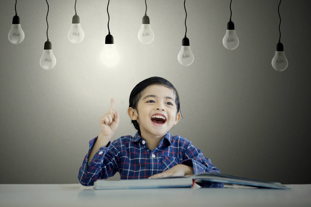 Милий маленький хлопчик вчиться під яскравою лампочкою
 - Фото, зображення