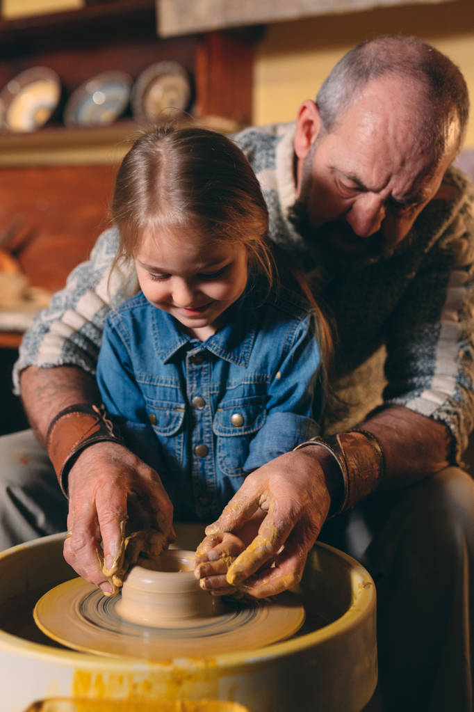 Atelier de poterie. Grand-père enseigne la poterie à petite-fille. Modélisation de l'argile - Photo, image