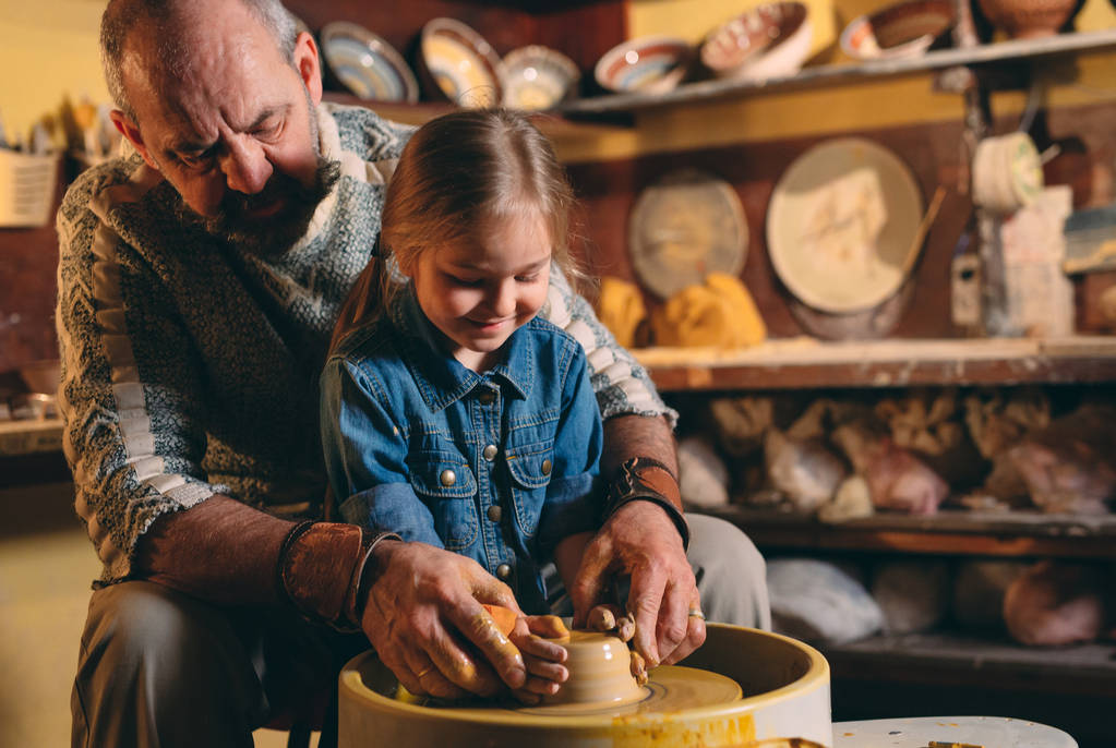 Керамическая мастерская. Дедушка преподает керамику внучке. Моделирование глины - Фото, изображение