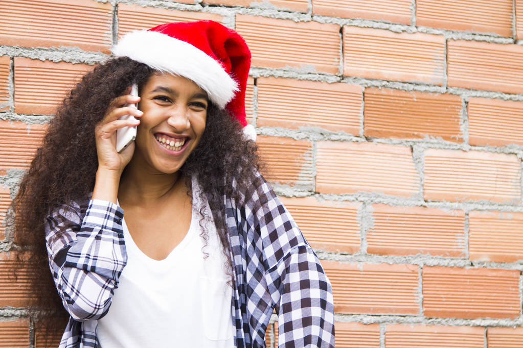 Noel Baba şapka ve cep telefonu ile Afro genç kadın - Fotoğraf, Görsel