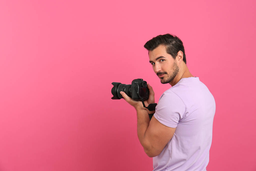 Young photographer with professional camera on pink background. Space for text - Photo, Image