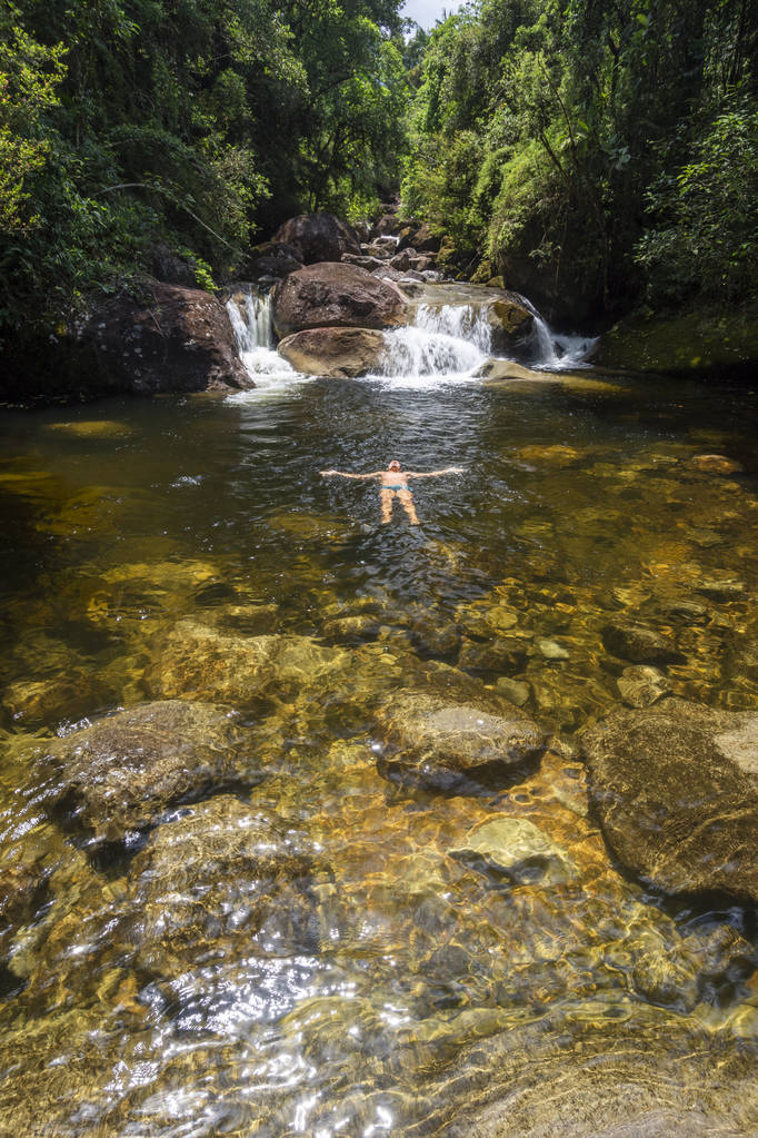 Hermosa cascada de selva tropical con persona flotando en el agua
 - Foto, imagen
