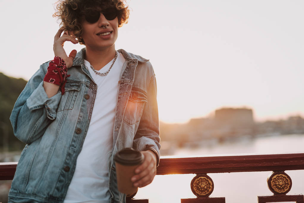 Zrelaksowany uczeń z kawą na moście - Zdjęcie, obraz