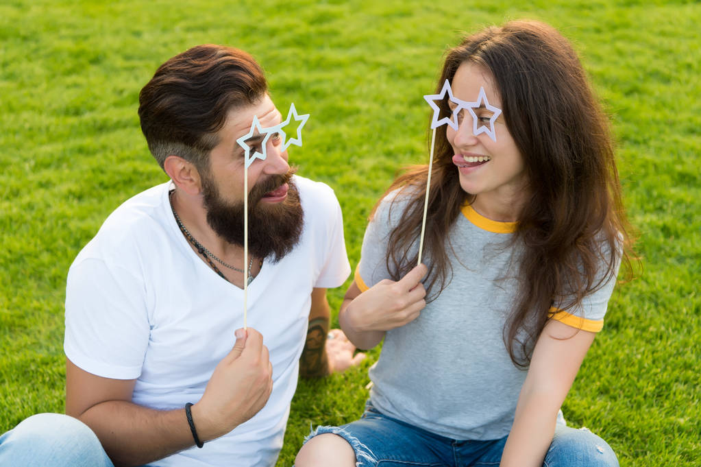 Couple in love cheerful youth booth props. Man bearded hipster and pretty woman cheerful faces. Youth day. Summer entertainment. Emotional people. Couple dating. Carefree couple having fun green lawn - Photo, Image