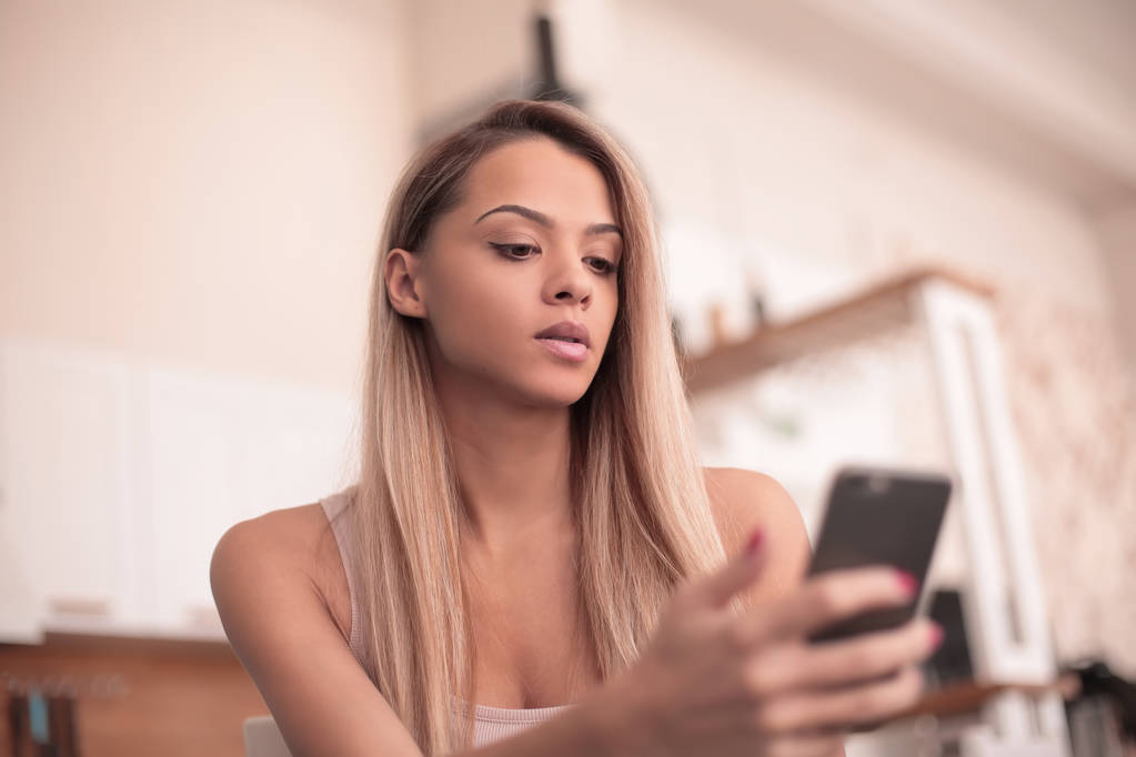 De cerca. mujer joven y seria leyendo SMS en su smartphone
 - Foto, imagen