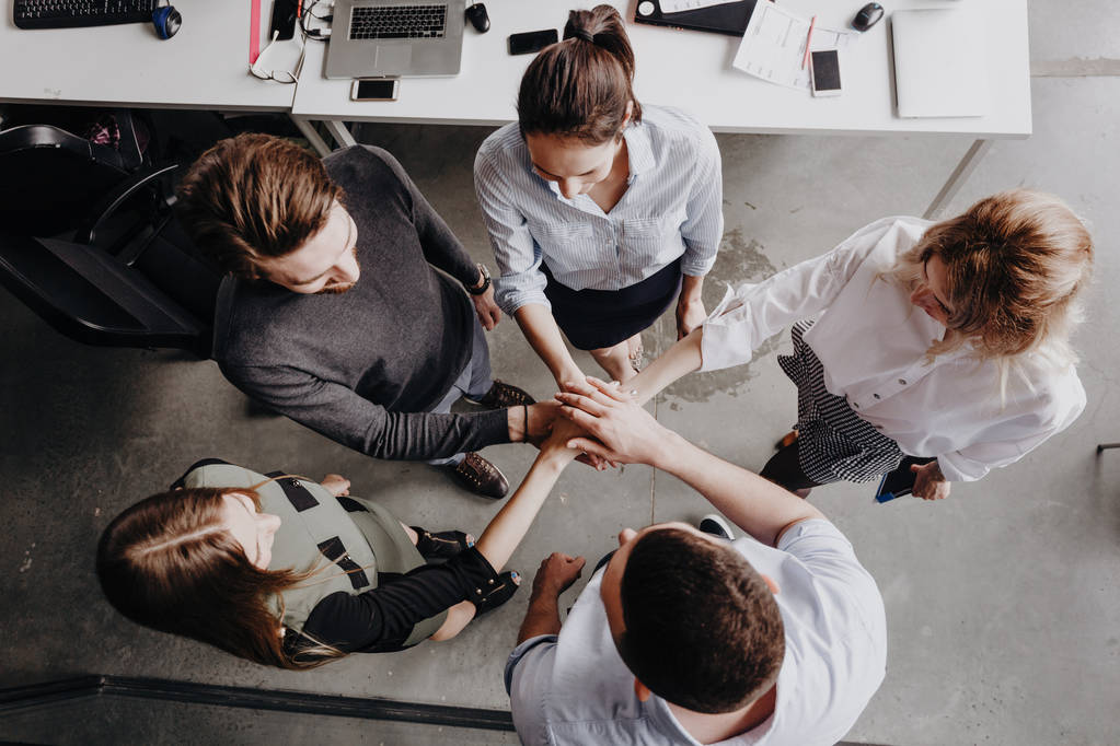 Team Building. O grupo de colegas está em um círculo dobrado as mãos um no outro no escritório moderno
. - Foto, Imagem