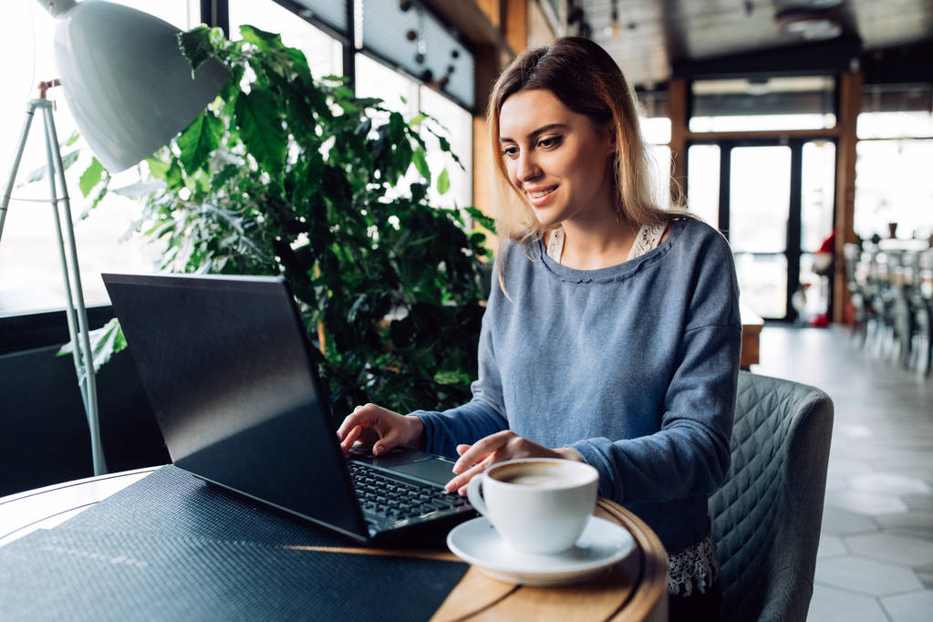 Femme souriante assise au café avec ordinateur portable
 - Photo, image