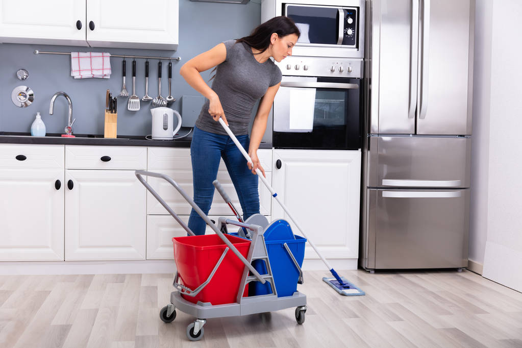 Onnellinen nainen talonmies puhdistus lattia moppi keittiössä
 - Valokuva, kuva