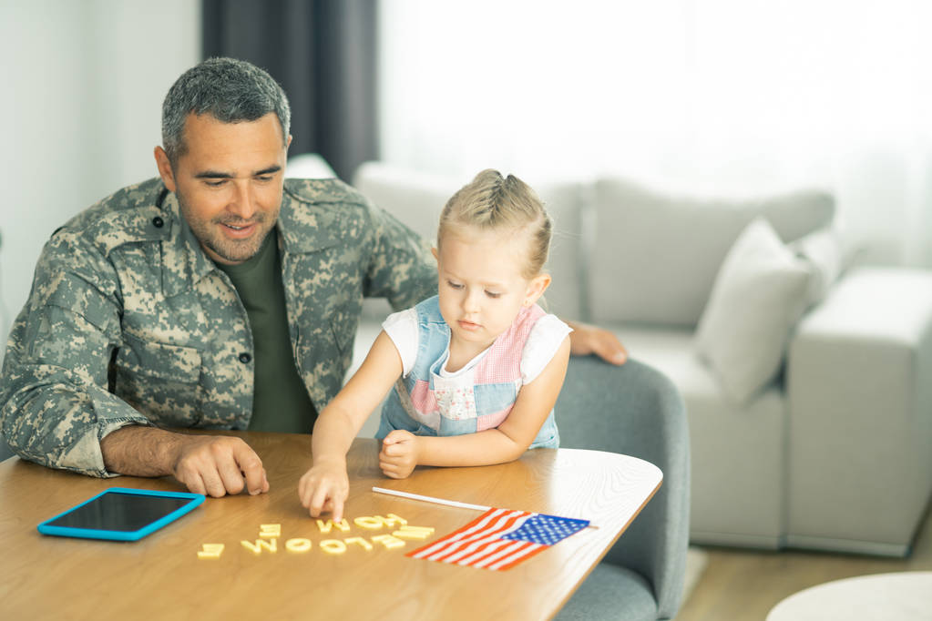 Lány üdvözölve apu visel katonai egyenruhát otthon - Fotó, kép