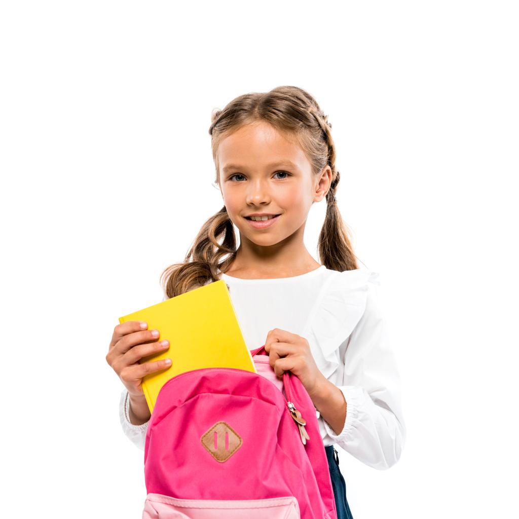 白に隔離されたピンクのバックパックに本を入れて笑顔の子供  - 写真・画像