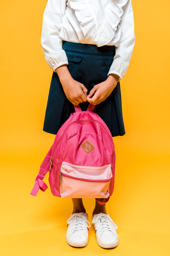 cropped view of schoolkid holding backpack and standing on orange  - Photo, Image